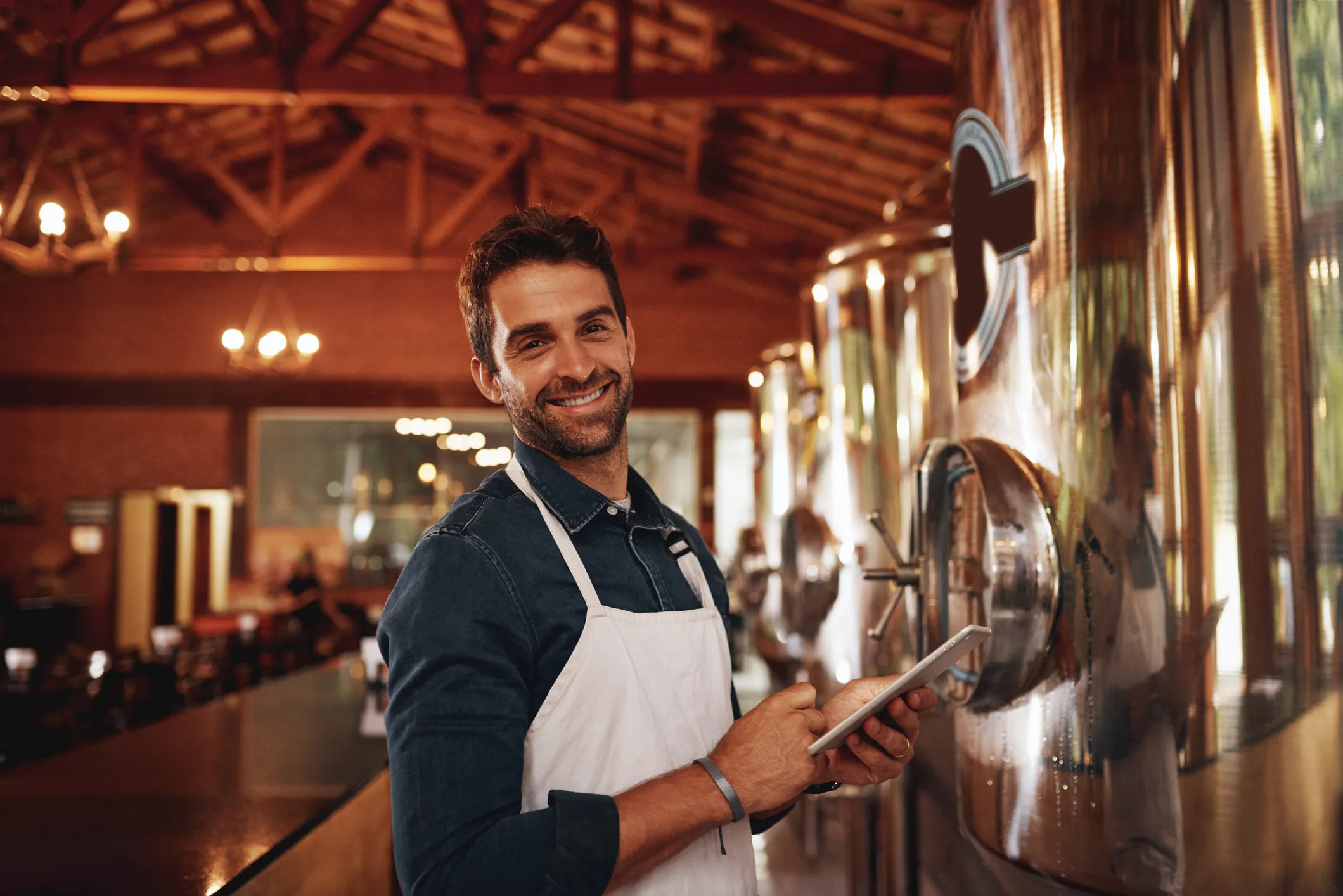 Person holding a tablet in front of winemaking equipments