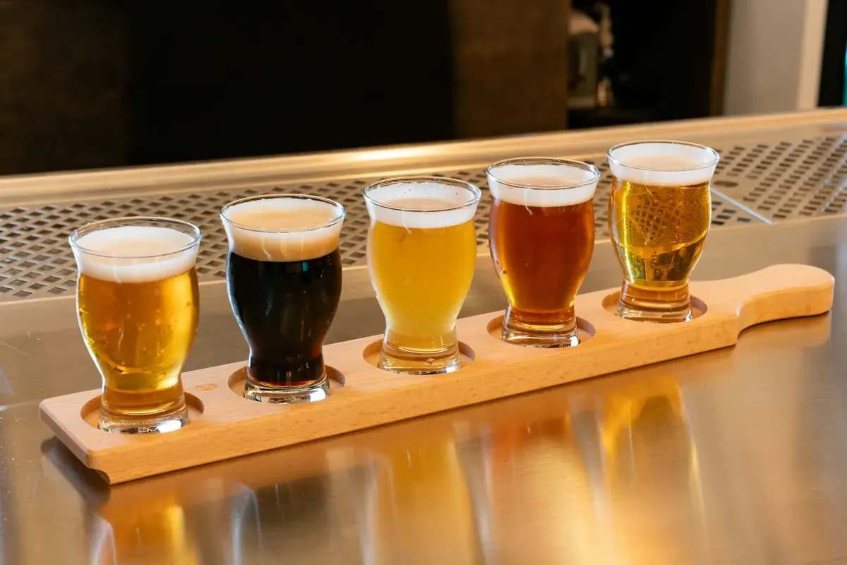 Five craft beer samples on a wooden flight paddle at the bar