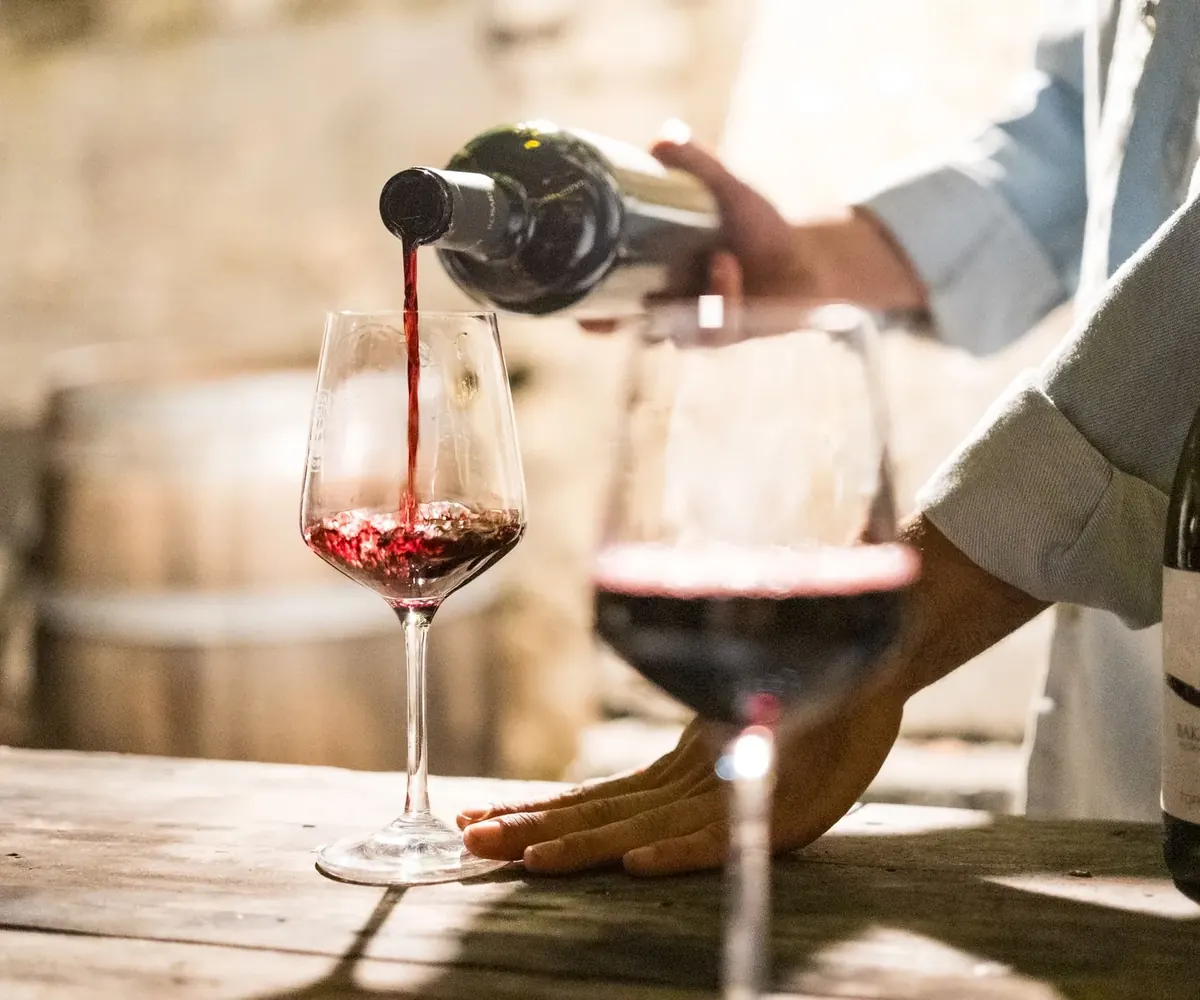 Red wine being poured into a glass at a tasting bar